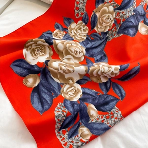 Detailed close-up of red floral silk scarf with cream roses and elegant chain patterns