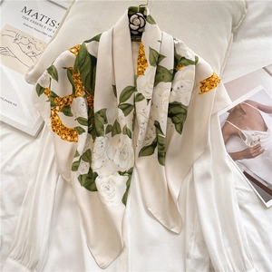 Macro detail of silk scarf with rose floral pattern and gold chain print on soft fabric
