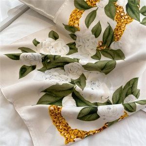 Macro detail of silk square scarf featuring camellia flowers and golden chain patterns