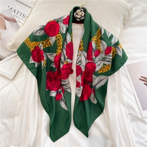 Detailed close-up of dark green silk scarf with red roses and gold chain patterns