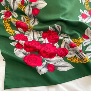 Detail of emerald green silk scarf featuring red rose floral prints and golden chains