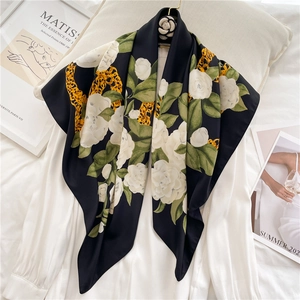 Detail of 90cm silk scarf featuring white camellia and golden chain patterns on black fabric