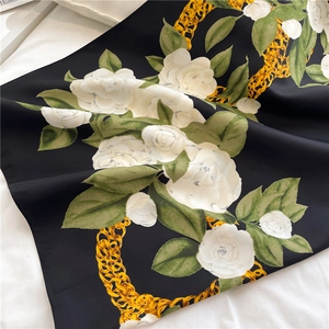 Close-up of matte silk scarf with white camellia flowers and golden chain pattern