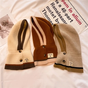 Three knit hooded scarves in cream, brown, and khaki with decorative buttons and labels
