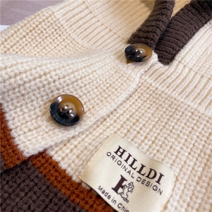 Close-up of beige knit cardigan with brown trim and textured amber-style buttons