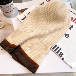 Close-up of thick cream knit balaclava featuring contrasting brown and orange stripes