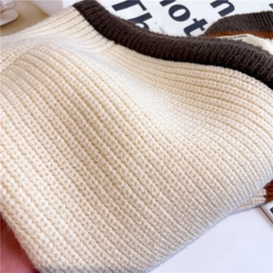 Detail of ribbed knit winter scarf showing cream and brown bicolor texture with a fabric label