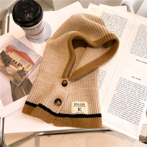 Detail of knitted hood scarf with buttons and HILLDI brand patch in cozy autumn setting