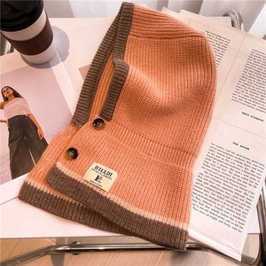Close-up of orange knit balaclava scarf with brown ribbing and button details