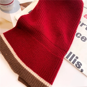 Detailed knit texture of dark red winter scarf with white and brown stripes on table