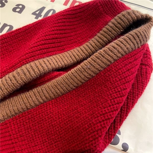 Detailed close-up of dark red and brown ribbed knit winter scarf with thick texture