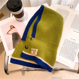 Close-up of green and blue knit shawl featuring retro buttons and a branded woven label
