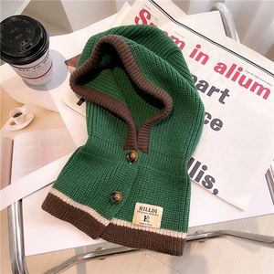 Detailed close-up of chunky knit balaclava hood with rustic wood buttons and brand tag