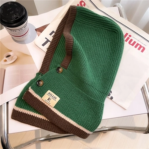 Detail of green knit balaclava with brown ribbed trim and amber button closures