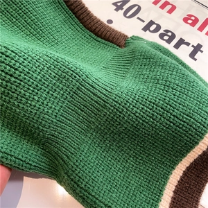 Close-up of thick forest green waffle knit sweater with brown and cream ribbed collar