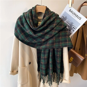 Thick warm dark green plaid scarf with soft fringe tassels on a wooden hanger