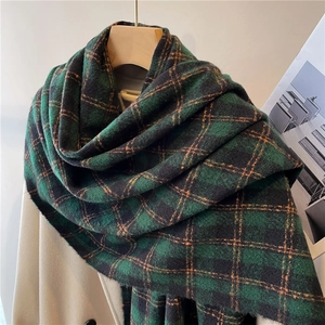 Detail of green and black plaid cashmere-like scarf with orange accents and soft tassels