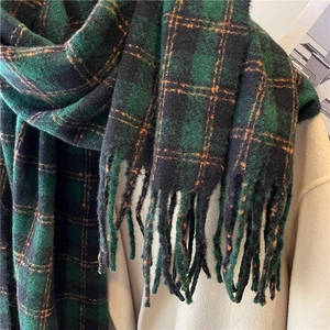 Close-up of green plaid cashmere-like scarf texture with fringe details on a coat