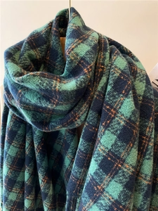 Close-up of thick plaid scarf in teal and navy blue with warm fuzzy knit texture