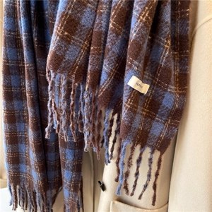 Close-up of blue and brown plaid scarf with fringe on a beige coat detail