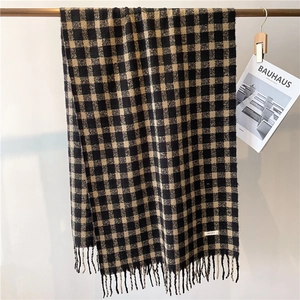 Close-up of black and yellow plaid scarf texture with soft fringe details on a rack