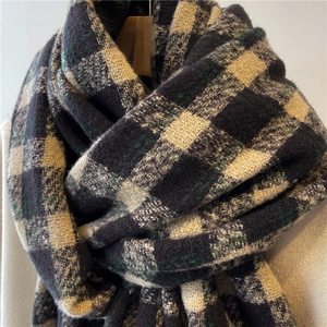Close-up of thick plaid knit scarf featuring dark blue and green checkered texture