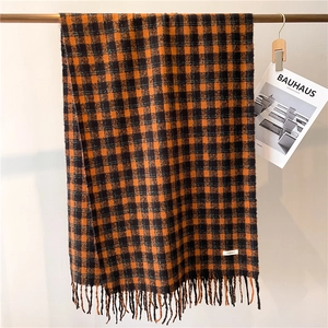 Thick warm orange and black plaid scarf with fringe and a minimalist woven label