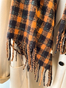 Close-up of orange and dark blue plaid scarf with soft fringe and thick cashmere-like texture
