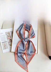 Detail of a luxury orange and blue patterned silk scarf with floral prints on a white base