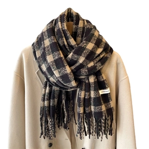 Thick black and beige plaid winter scarf with fringe tassels on a wool coat