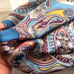 Macro detail of silk scarf showing paisley pattern and vibrant satin fabric texture
