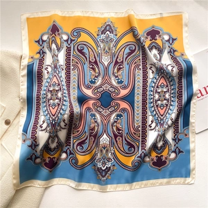 Detail of European paisley silk square scarf paired with a stylish tweed jacket on white surface