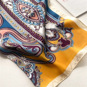 European paisley silk scarf for women in vibrant multicolor folds on a white surface