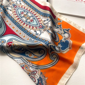 Detailed view of paisley pattern silk scarf with vibrant orange and blue color blocks
