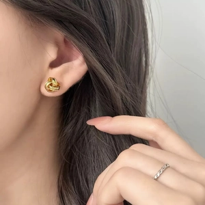 Boucles d'oreilles clous dorées torsadées élégantes avec texture raffinée sur modèle