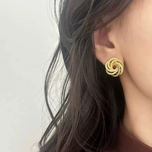 Boucles d'oreilles torsadées dorées avec texture tissée portées par un mannequin