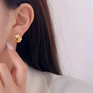 Boucles d'oreilles nœud torsadé doré pour femme avec une texture métallique polie