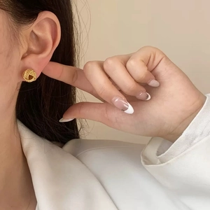 Gros plan d'élégantes boucles d'oreilles nœuds torsadés dorés portées par un mannequin
