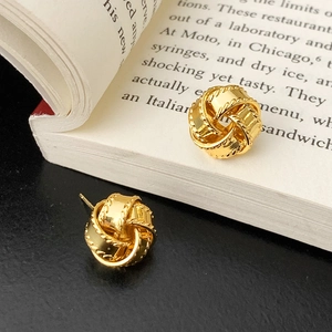 Gros plan de boucles d'oreilles nœuds dorés tressés avec texture cordelette sur livre