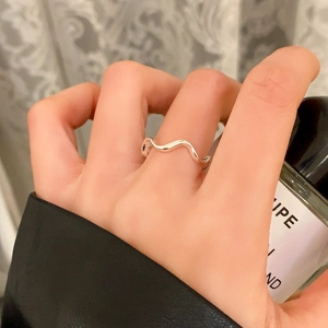 Close-up of minimalist wave ring in polished silver metal on index finger