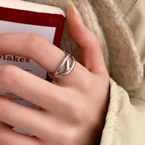 Dettaglio di un anello a incrocio multistrato argento su mano per un look minimalista