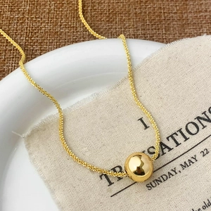 Collier élégant avec perle dorée et finition miroir minimaliste sur plateau céramique