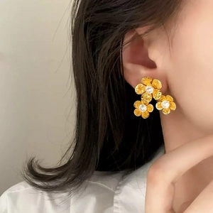 Elegante goldene Blumenohrringe mit Hammerschlagstruktur und Diamanten am Ohr getragen