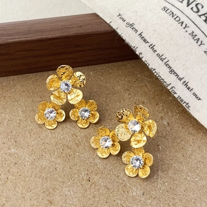 Makro-Detail der goldenen Blumenohrstecker mit Hammerschlag-Optik und Zirkonia-Steinen