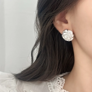 Elegant silver abstract rose stud earrings with metallic petals on female model