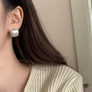 Close-up of geometric matte silver square stud earring on model for elegant styling