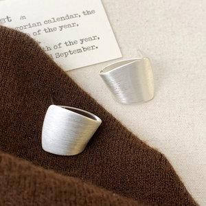 Macro detail of silver brushed rectangular earrings on cozy autumn knit fabric textures