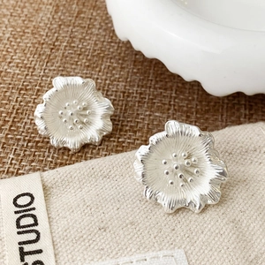 Detailed macro view of silver floral earrings with delicate textured petals and stamen