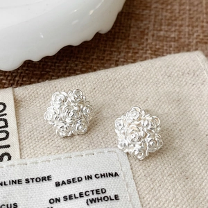 Detailed close-up of silver rose stud earrings with layered floral cluster petals