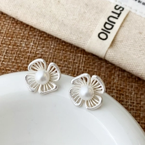 Detail showing silver hollow flower earrings with central white pearls and fine textures